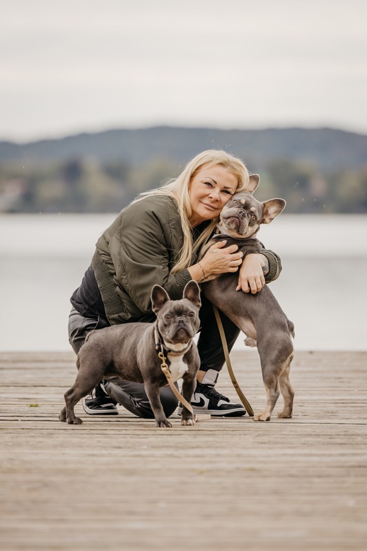 Frau mit zwei französischen Bulldoggen am Seeufer